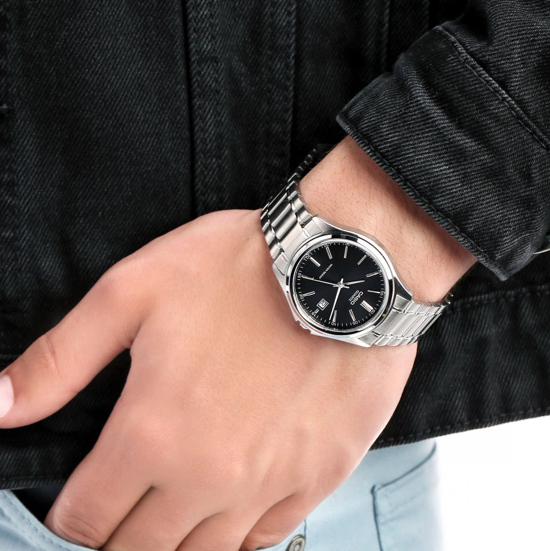 Reloj Casio MTP-1239D-1A original para hombre lucido en muñeca, con esfera negra, caja plateada y correa de acero inoxidable.