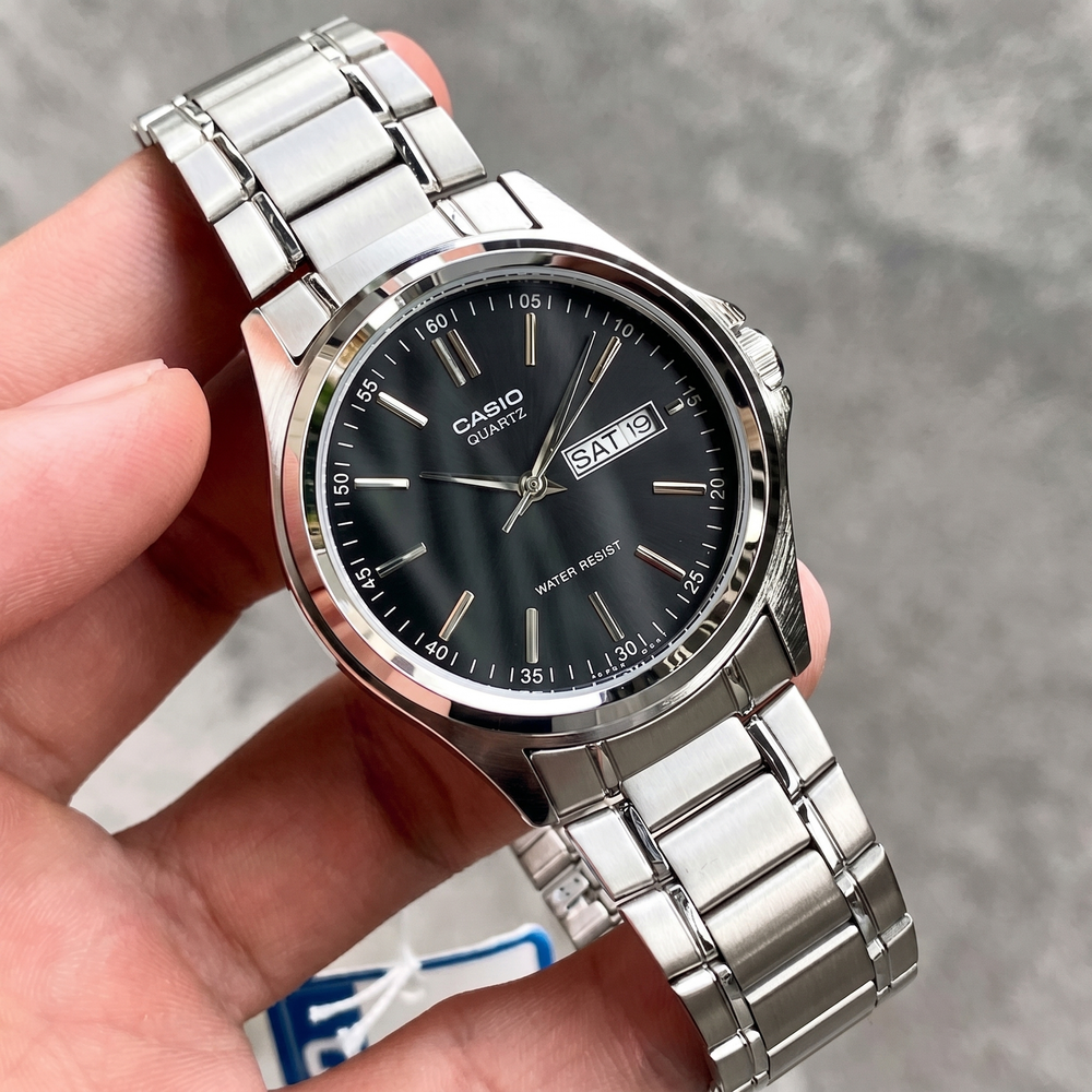 Reloj Casio MTP-1239D-1A original para hombre sostenido en la mano, con esfera negra y correa de acero inoxidable plateada.